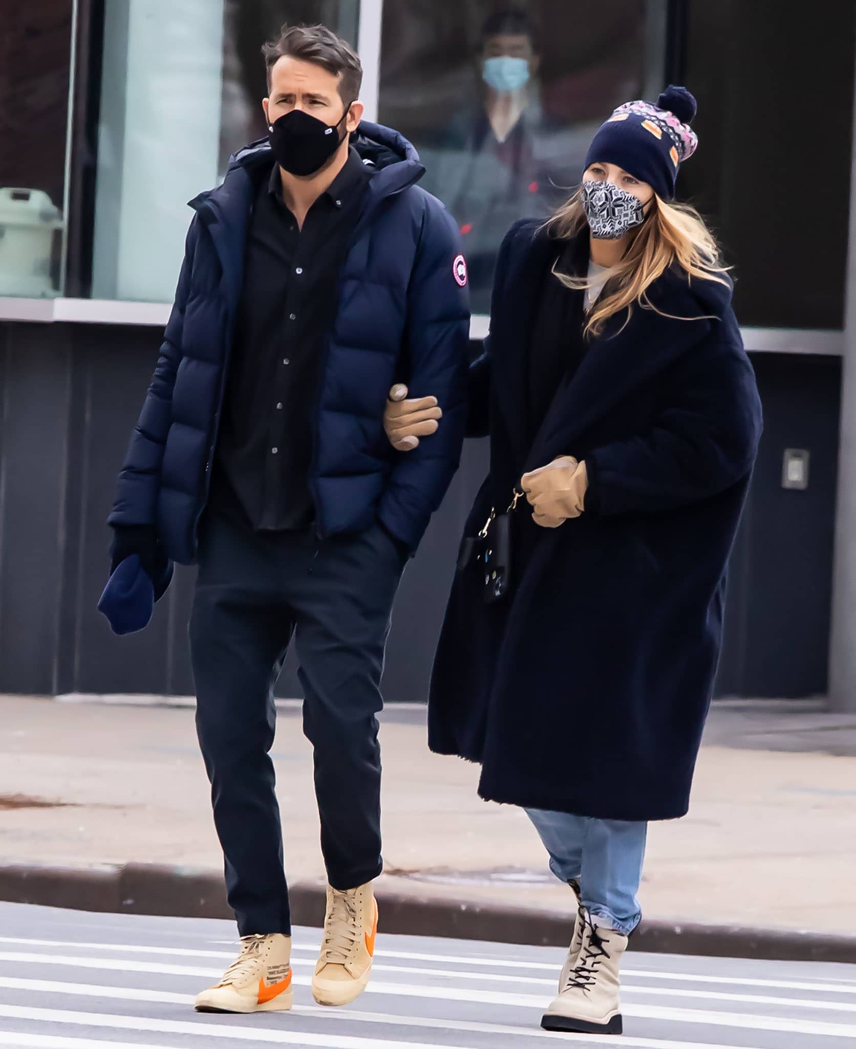Ryan Reynolds and Blake Lively coordinate in deep navy layers while crossing a New York street on January 24, 2022—he adds a pop of color with Off-White x Nike Blazer sneakers, while she grounds her oversized Max Mara coat and light-wash denim with cream suede Rag Bone “Sloane” combat boots