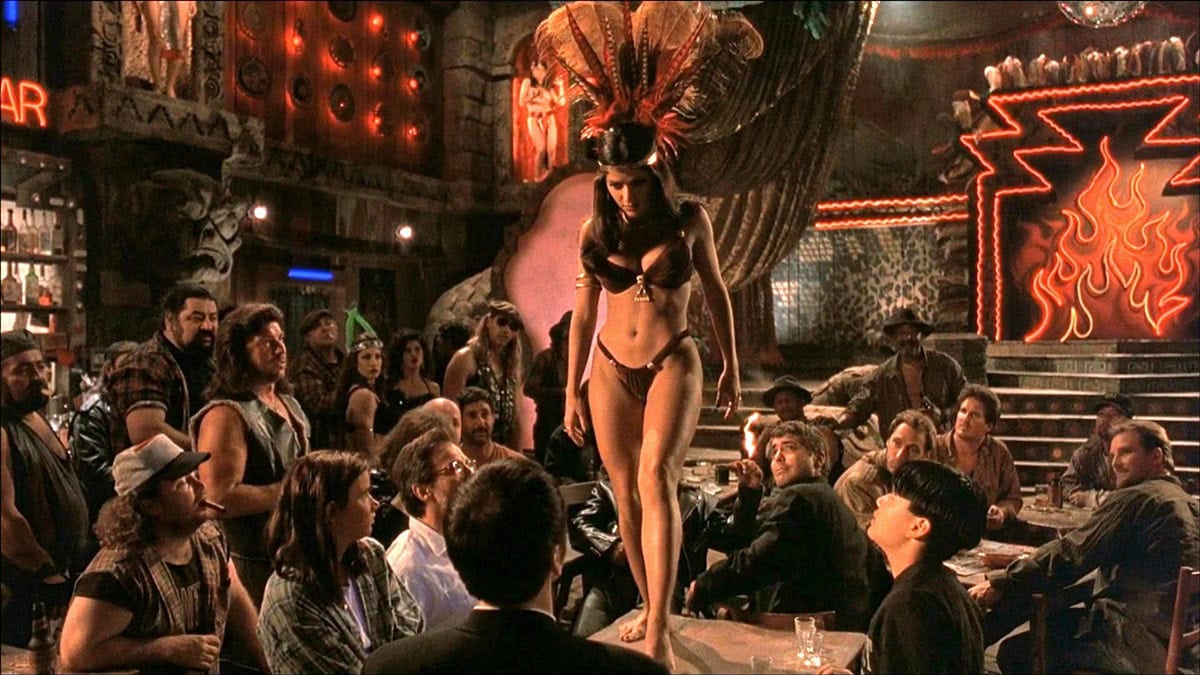 Salma Hayek Pinault stuns as Santanico Pandemonium in From Dusk Till Dawn, wearing an iconic feathered headdress and bejeweled bikini that defined one of the most unforgettable dance scenes in cult film history