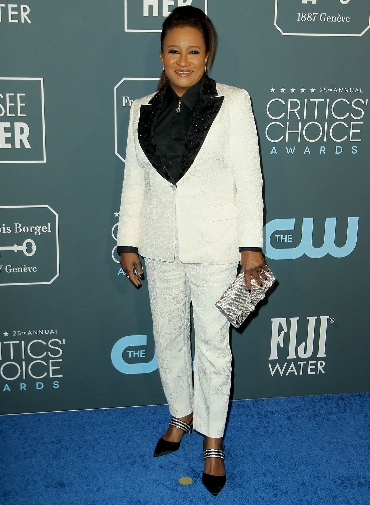 Wanda Sykes exudes polished charm in a textured white tuxedo suit layered over a black shirt, finishing her Critics' Choice Awards look with a bold, glamorous edge thanks to the sparkling ‘Treena’ slingback heels from Nina Shoes, adorned with triple ankle straps