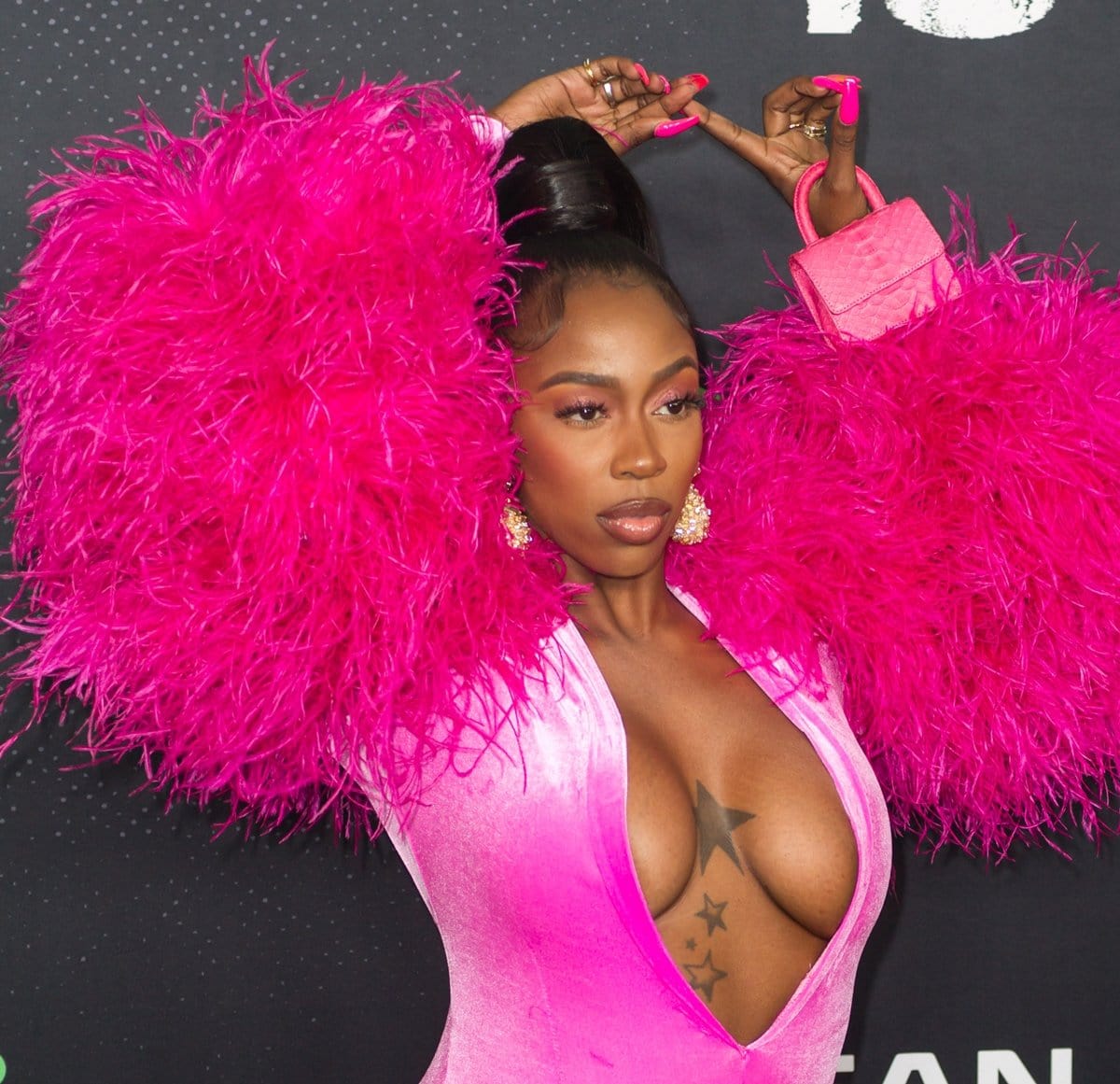 Rapper Kash Doll stole the spotlight in a dramatic hot pink feathered gown with a plunging neckline, gold statement earrings, and matching manicure and mini handbag for a fierce and glamorous red carpet moment