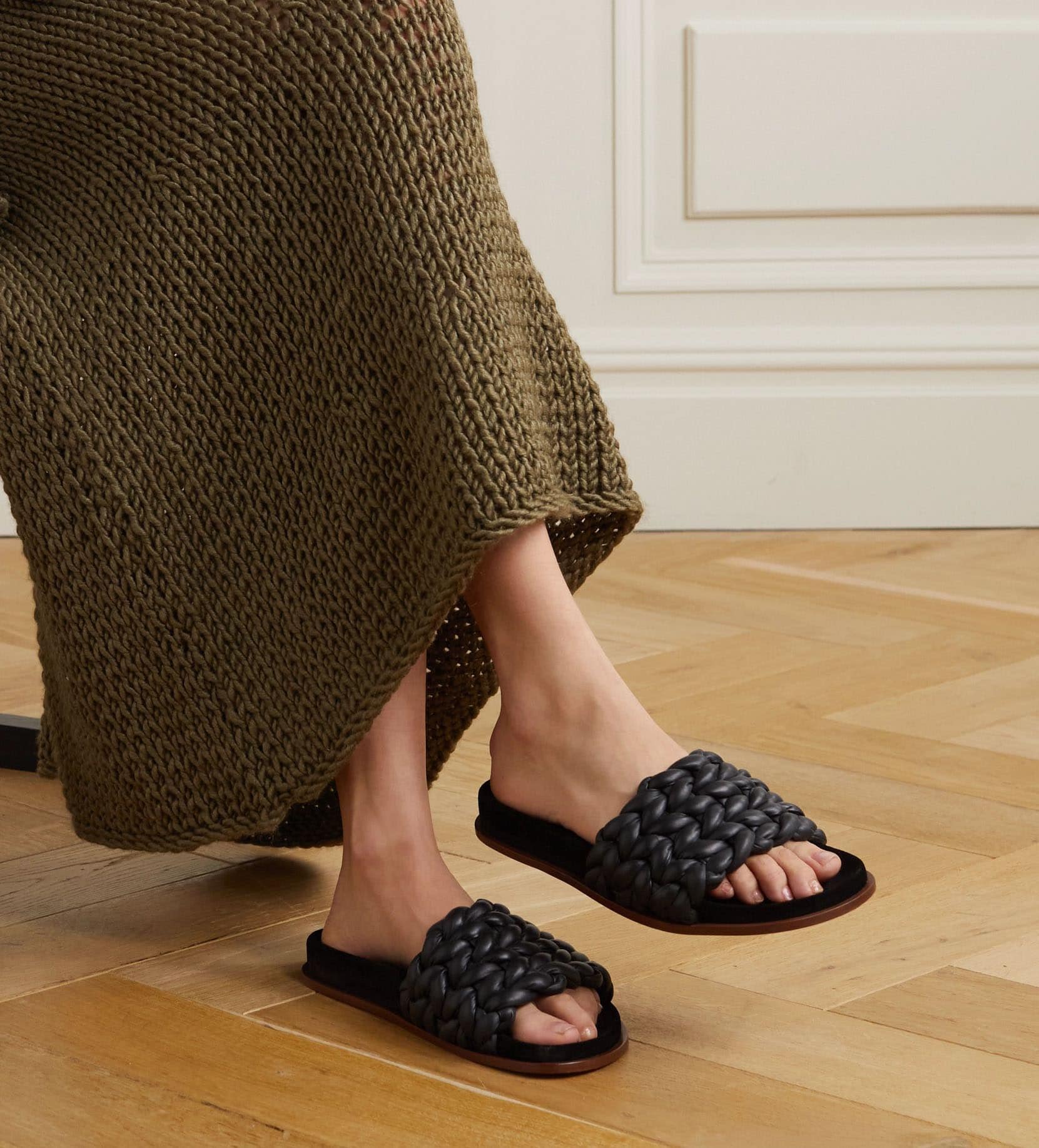 A close-up highlights the Chloé Kacey slides, showcasing their hand-woven, braided leather upper and low-profile sole designed for effortless everyday wear