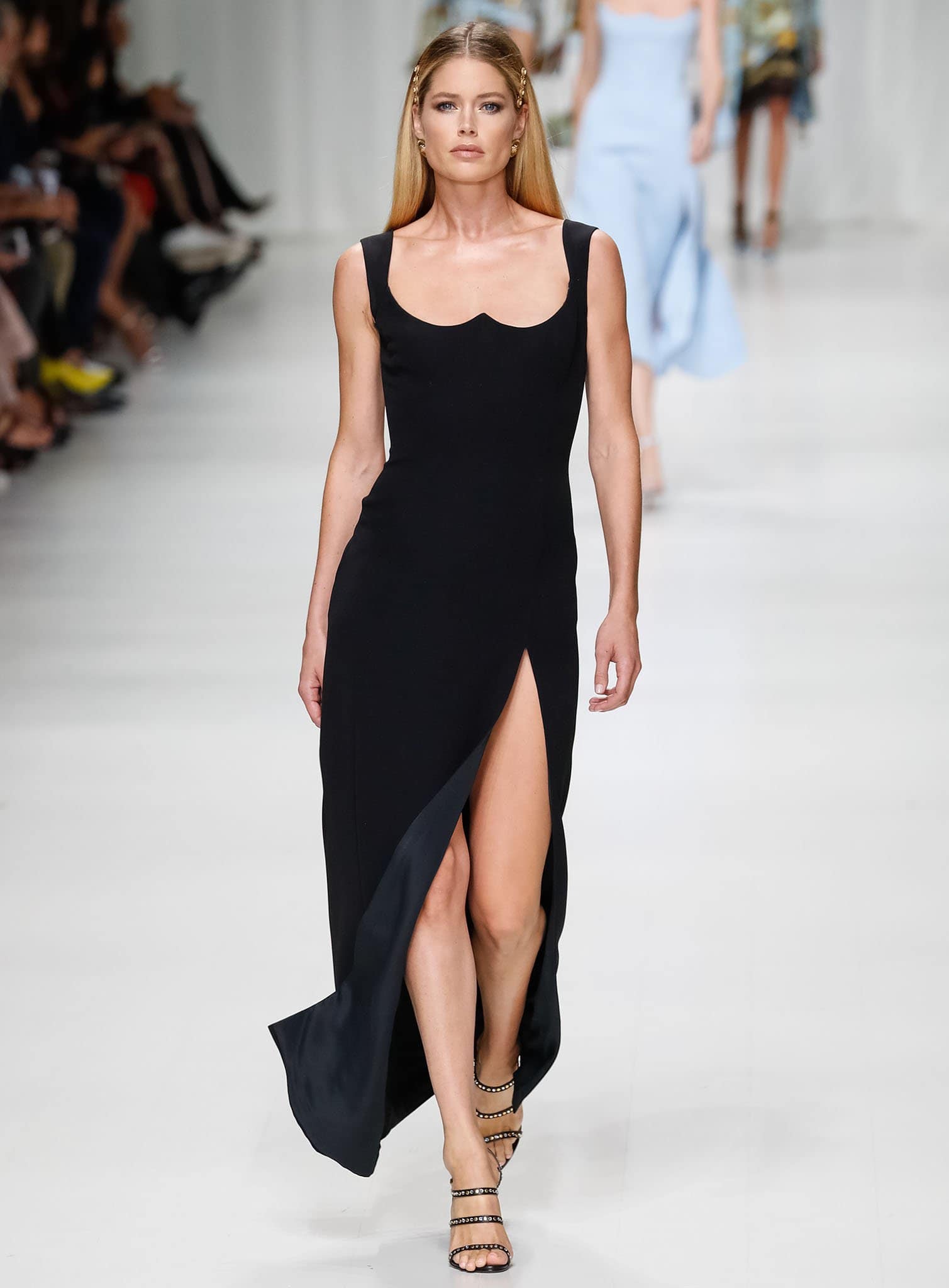 Doutzen Kroes, standing at 5 feet 9 ¼ inches (175.9 cm), captivates on the runway in a sleek black thigh-slit gown paired with studded strappy heels that highlight her long legs and powerful, poised stride