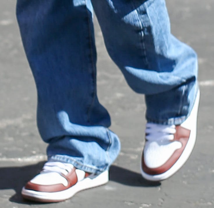Hailey Bieber completes her relaxed streetwear look with white-and-team-red Nike Air Jordan 1 Low sneakers, pairing the classic basketball silhouette with oversized cargo jeans