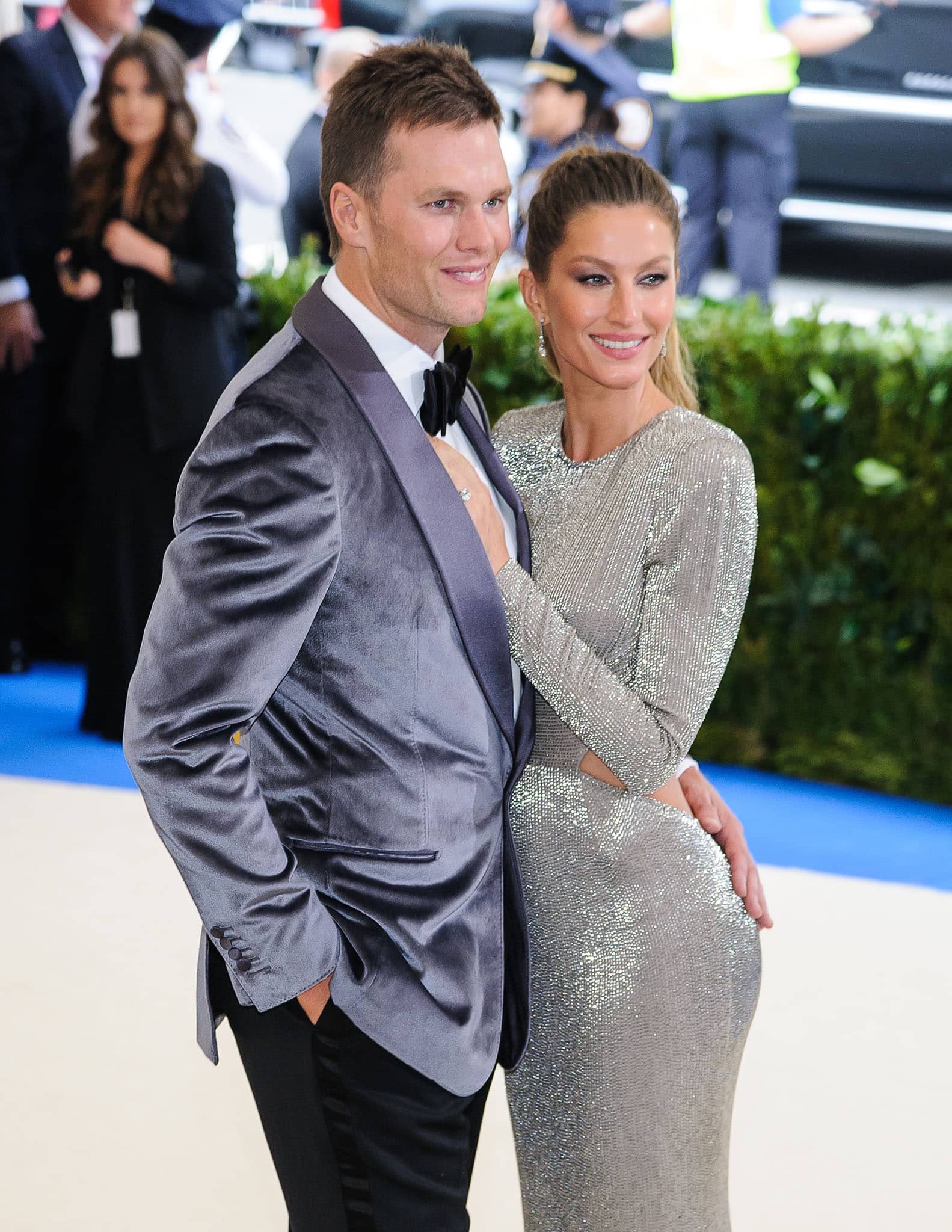 Gisele Bündchen, standing tall at 5ft 10 (177.8 cm), sparkles in a form-fitting silver backless gown while posing with Tom Brady in a velvet tuxedo jacket