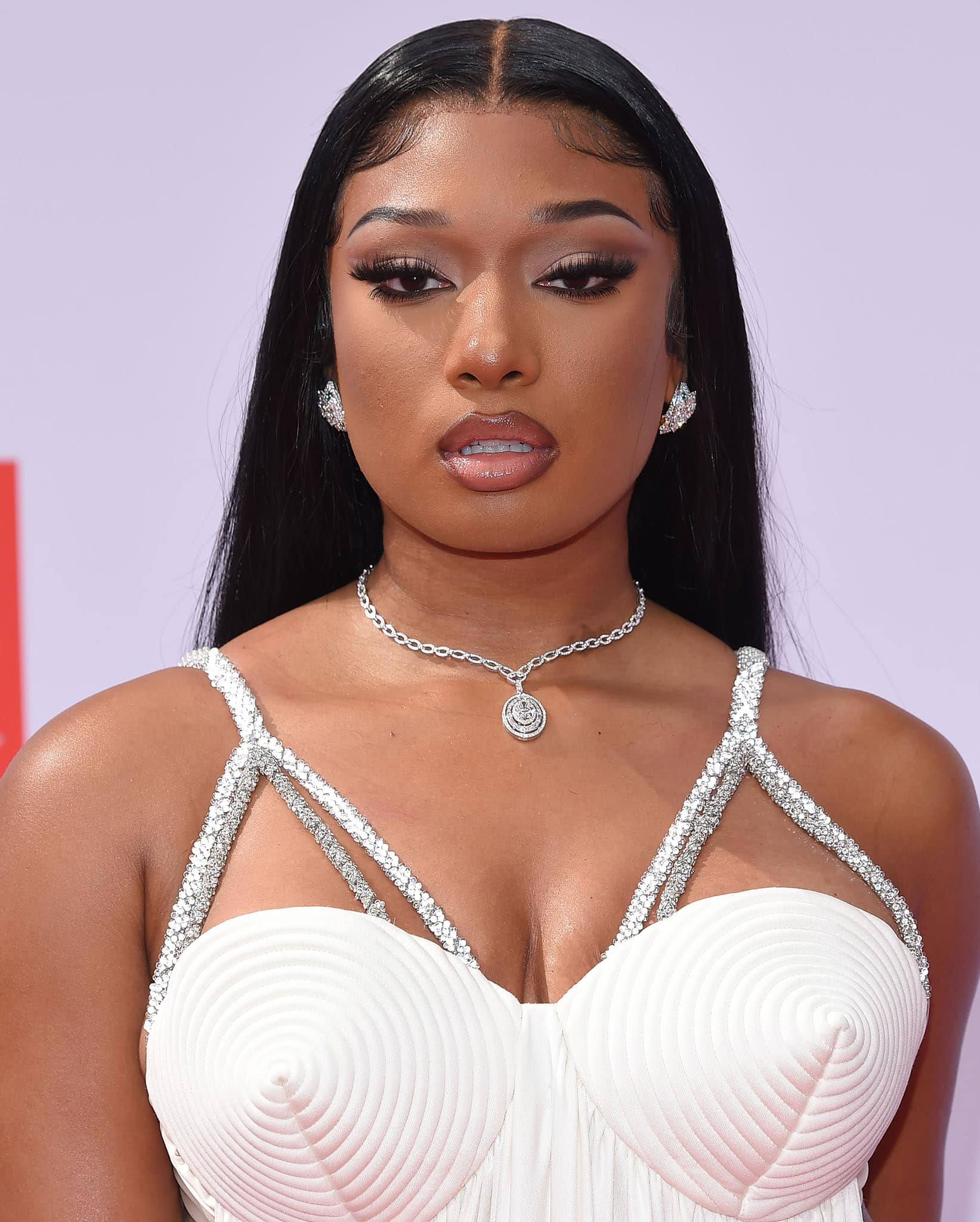 Megan Thee Stallion stuns in a glamorous white dress adorned with intricate silver straps and a statement diamond necklace
