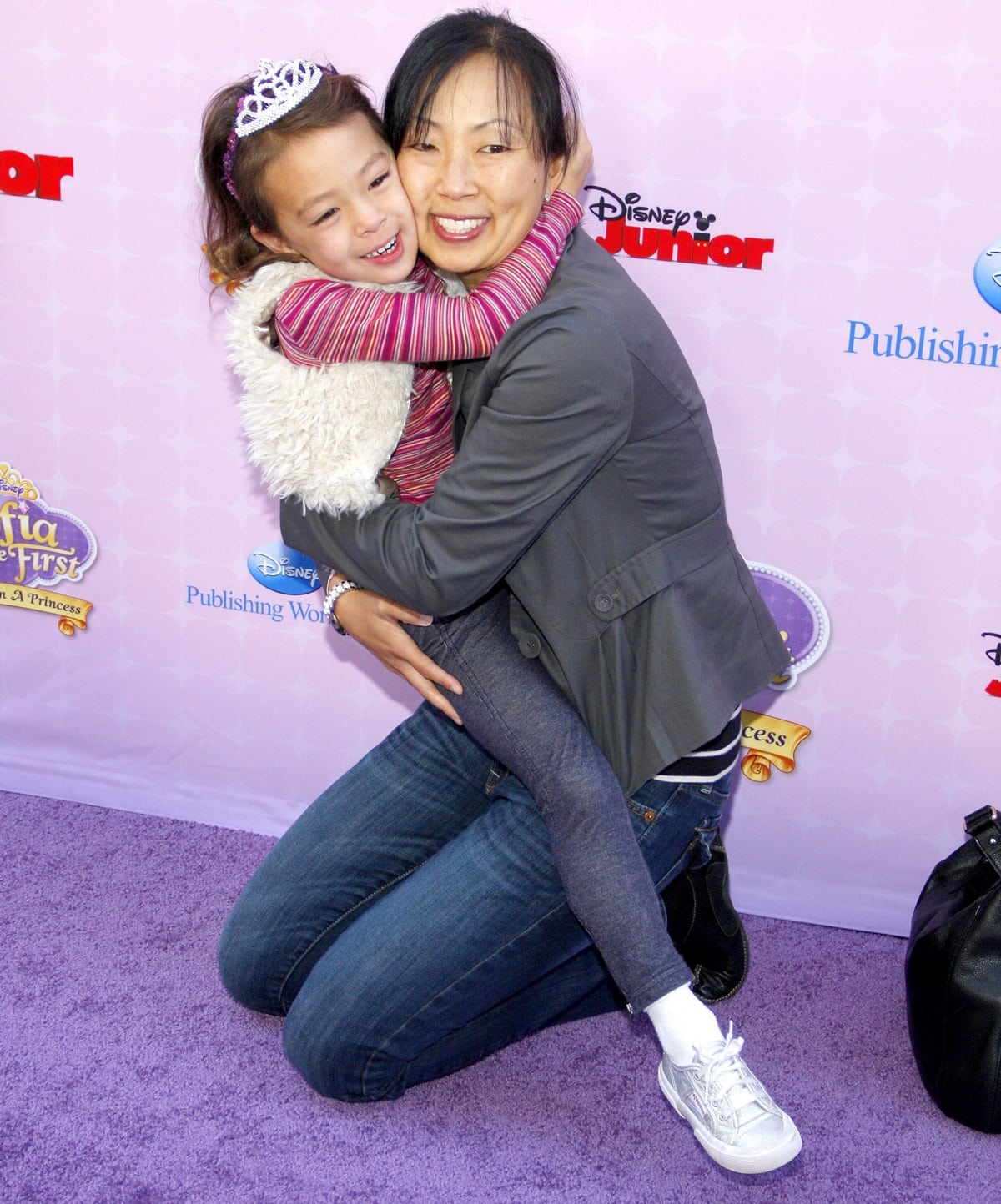 A young Aubrey Anderson-Emmons shares a joyful hug with her Korean-American mother, Amy Anderson, at the Disney Channel's premiere party for Sofia the First: Once Upon a Princess on November 10, 2012, at Walt Disney Studios in Burbank, California