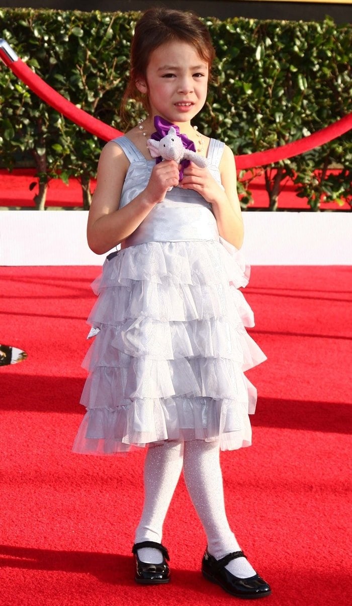 Aubrey Frances Anderson-Emmons looks adorable in a silver ruffled dress, sparkly white tights, and black patent Mary Jane shoes on the red carpet, charming fans with her youthful elegance
