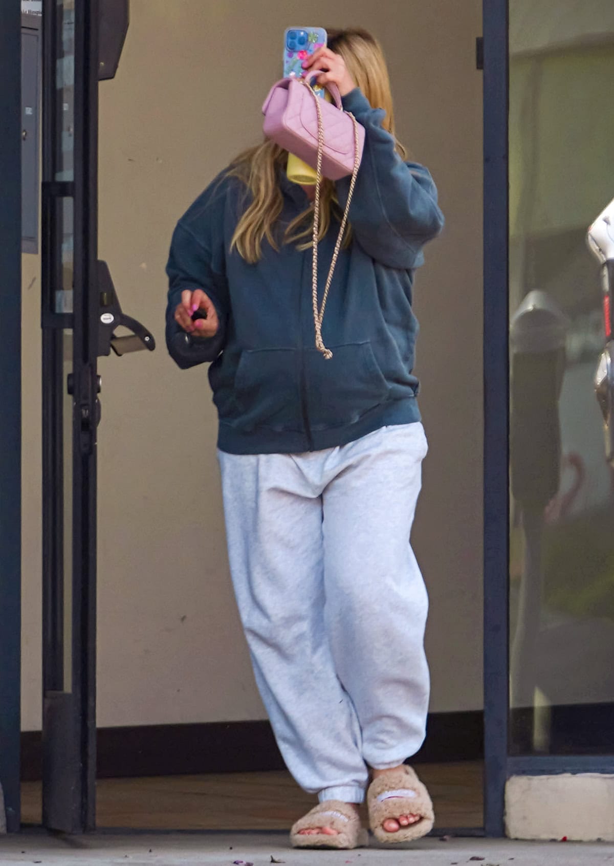 Hilary Duff conceals her face with a chic Chanel handbag while stepping out in casual style, sporting Balenciaga slide sandals and carrying an Owala water bottle in Sherman Oaks on April 18, 2024