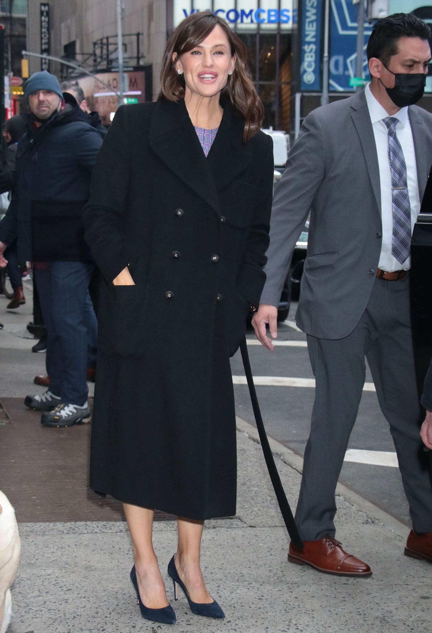 Jennifer Garner steps outside the GMA studios in a long black coat, revealing her chic navy suede pumps that elevate the polished morning look