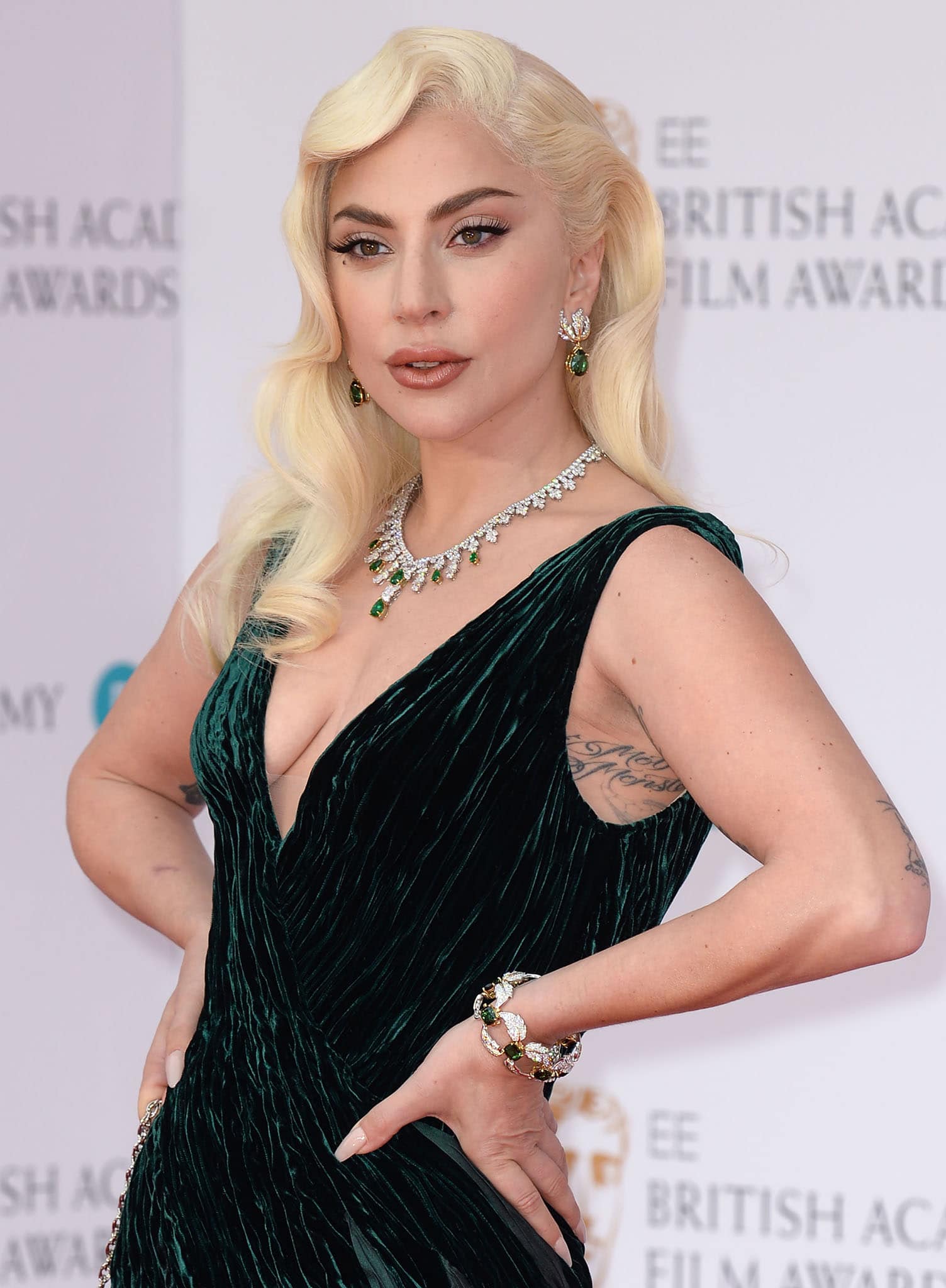 Lady Gaga styles her forest green gown with emerald jewelry by Tiffany Co. and wears old Hollywood curls and makeup
