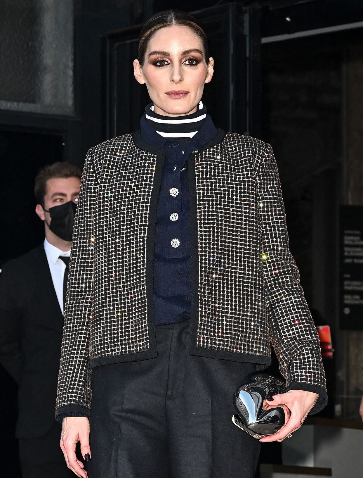 Olivia Palermo completes her Paris Fashion Week look with dramatic smokey eye makeup, a sleek center-parted bun, and minimal accessories that let her embellished jacket shine