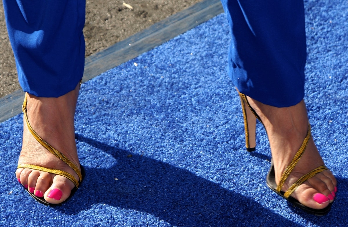 Tyra Banks shows off her size 12 feet in bold yellow strappy stilettos, perfectly paired with a bright pink pedicure on the blue carpet