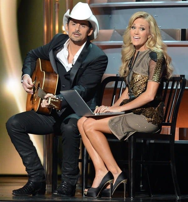 Brad Paisley and Carrie Underwood host the 2013 Country Music Awards, with Underwood wearing an Alpana Neeraj Fall 2013 dress, Rupert Sanderson “Hydra” open-toe platform pumps, and Melinda Maria Hepburn gold pod earrings