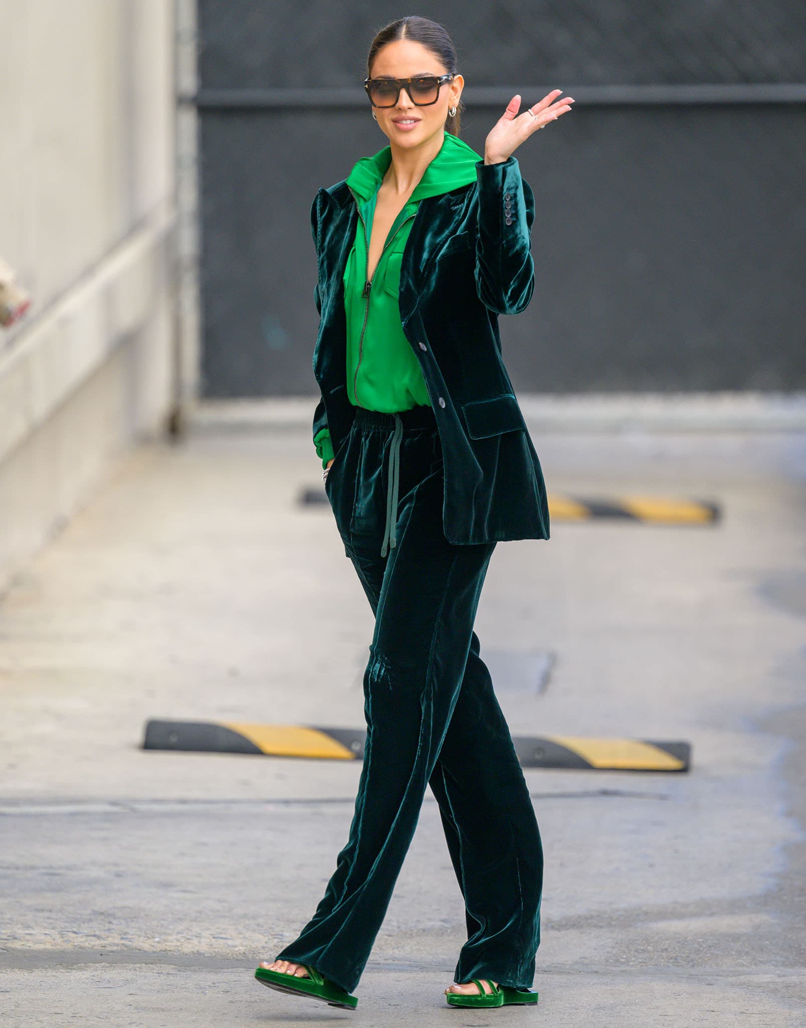 Eiza González heads to Jimmy Kimmel Live! on April 4, 2022, in a striking all-green Tom Ford look, pairing a plush velvet suit and neon hoodie with matching velvet sandals