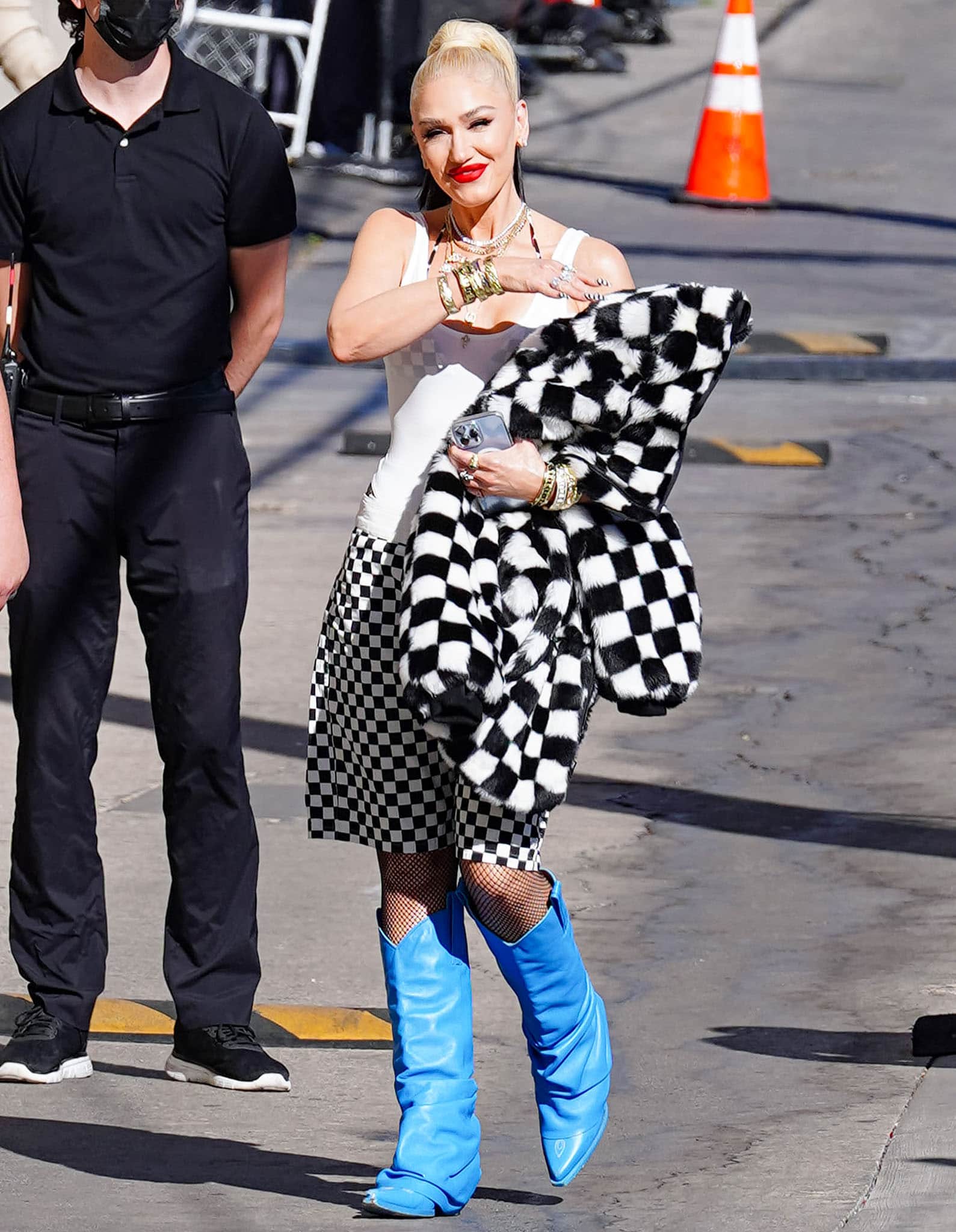 Gwen Stefani arrives at Jimmy Kimmel Live! on March 24, 2022, promoting her GXVE beauty line in a bold checkered ensemble finished with electric-blue R13 mid-cowboy boots that pop against fishnet stockings