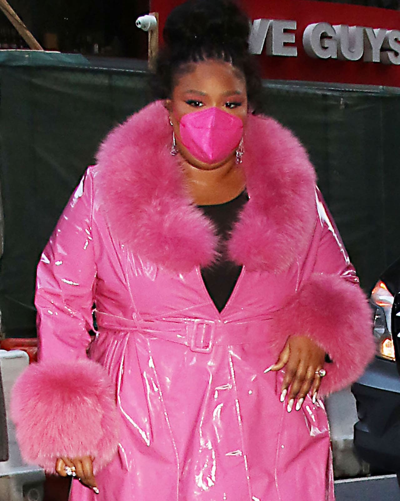 Lizzo wears a braided updo, pink eyeshadow, drop earrings, and a matching pink face mask while promoting her Yitty shapewear collection