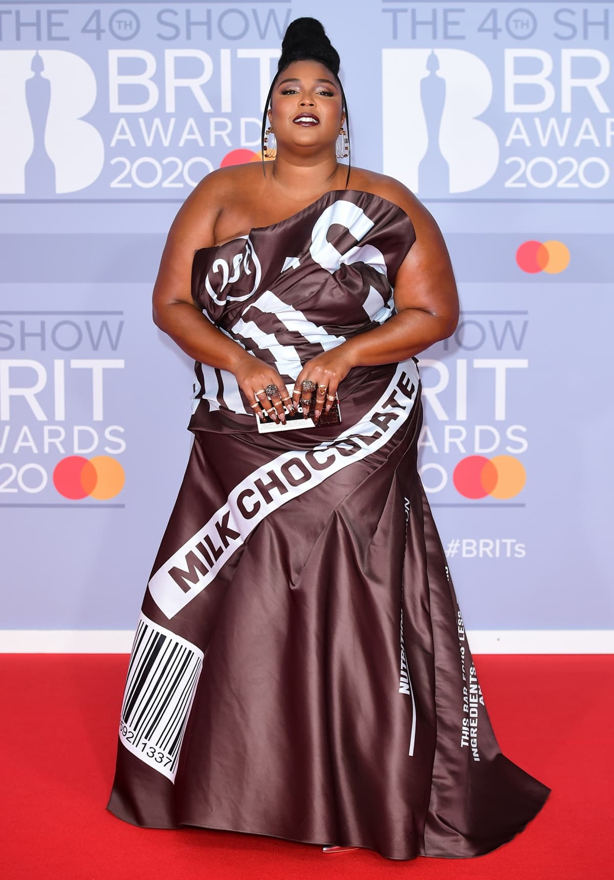 Lizzo wears metallic heels with a Jeremy Scott for Moschino dress inspired by the American chocolate brand Hershey’s for The BRIT Awards 2020