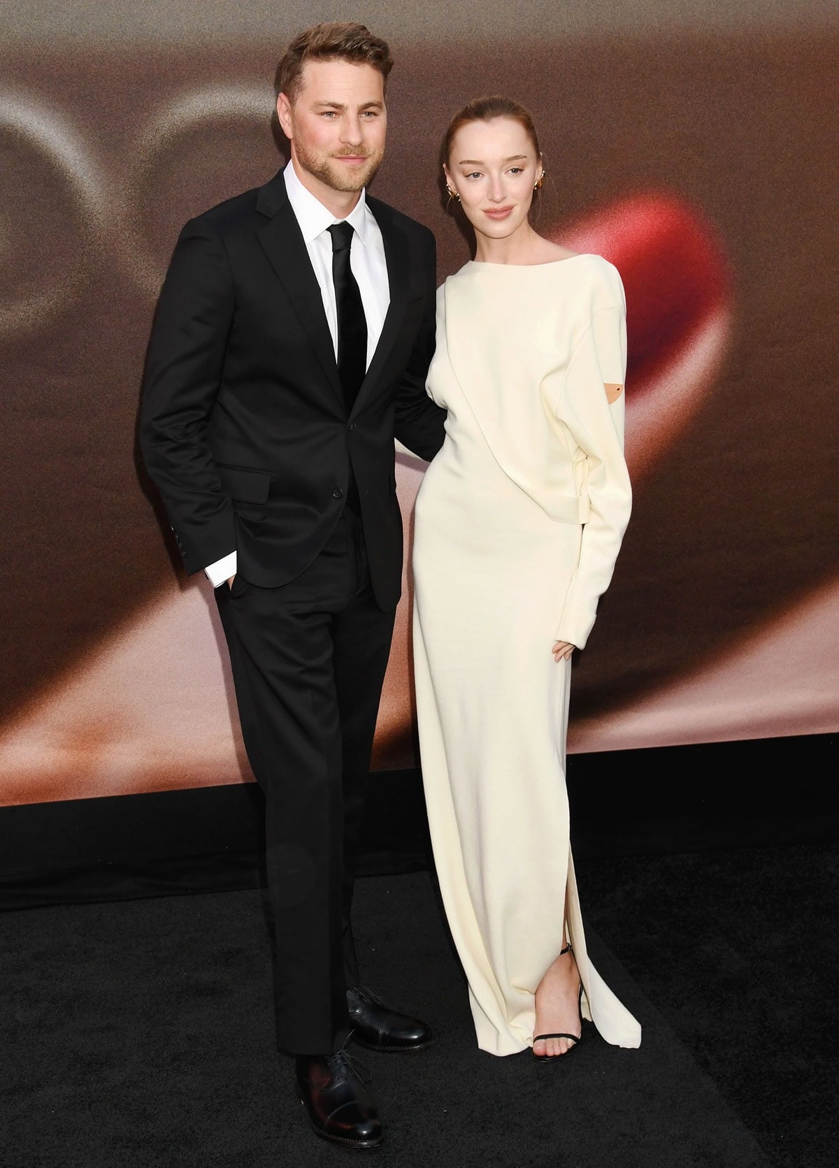 Phoebe Dynevor walked the red carpet with fiancé Cameron Fuller, wearing a minimalist white Louis Vuitton gown styled with Jimmy Choo Minny sandals and Tiffany Co. Elsa Peretti 18K gold Bean earrings at the Los Angeles premiere of The Drop on April 8, 2025