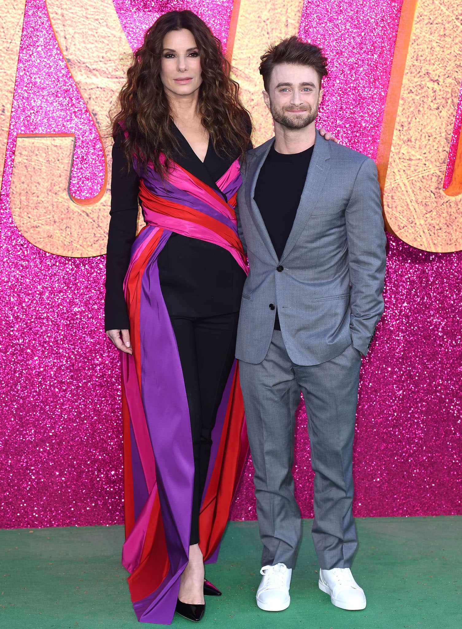 Sandra Bullock, in Carolina Herrera and Jimmy Choo pumps, towers over Daniel Radcliffe, who wears a gray Dior Homme suit with a black knit sweater and white Christian Louboutin sneakers
