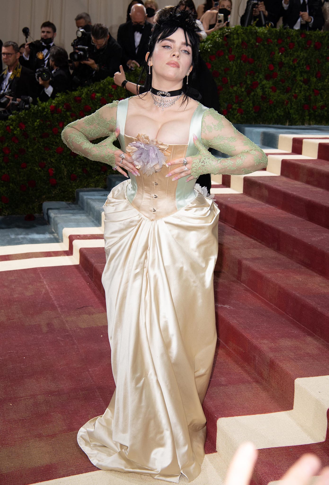 At the 2022 Met Gala in New York City, Billie Eilish reimagined the “Gilded Glamour” theme in a custom Gucci gown crafted from upcycled materials, blending corseted structure, draped ivory satin, and sheer mint lace with her signature gothic edge for a romantic yet subversive red-carpet moment