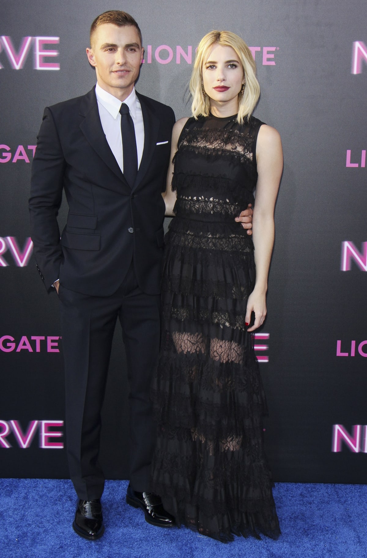 Emma Roberts layers a sheer black Elie Saab gown over platform sandals while Dave Franco complements in a sharp dark suit with classic leather dress shoes at the Nerve New York premiere