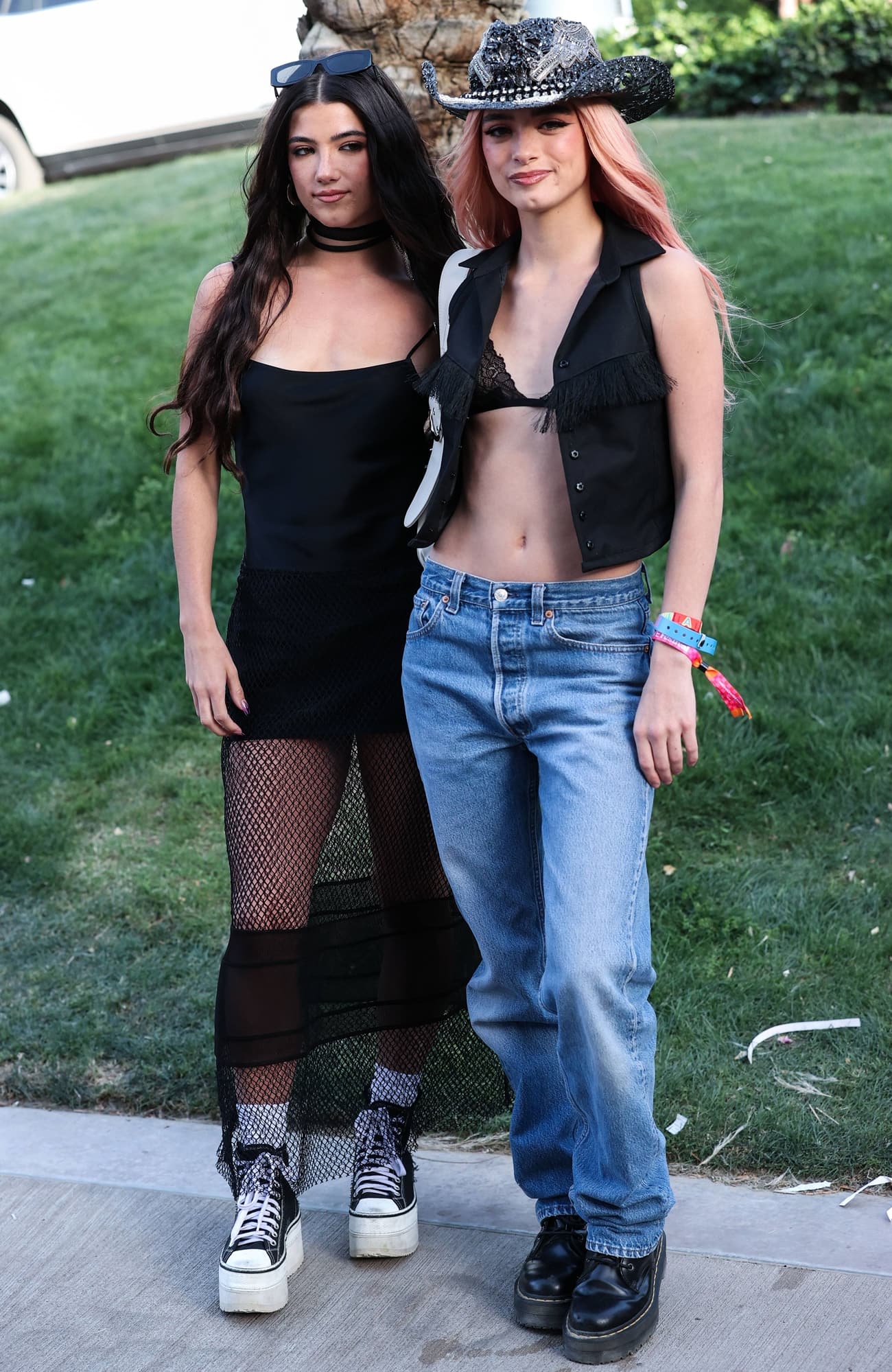 Charli D’Amelio paired a sheer black mesh dress with towering Converse Run Star-style platform sneakers, while sister Dixie D’Amelio contrasted low-rise jeans and chunky black boots with a fringed vest and embellished cowboy hat