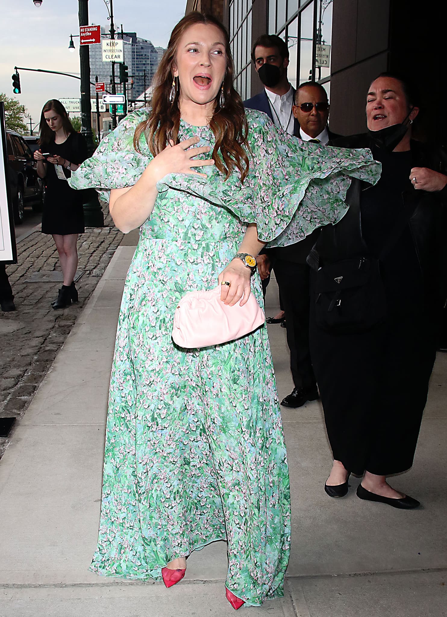 Drew Barrymore radiates joy on arrival at Variety’s Power of Women event, wearing a breezy Giambattista Valli floral silk maxi dress styled with a blush clutch and red Amina Muaddi heels