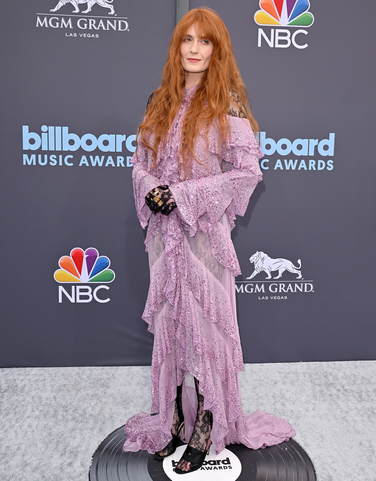 Florence Welch lets the layered Gucci gown cascade around her tall 5ft 8½-inch frame, pairing the lavender sequined ruffles with black lace gloves and dramatic ginger waves at the 2022 Billboard Music Awards