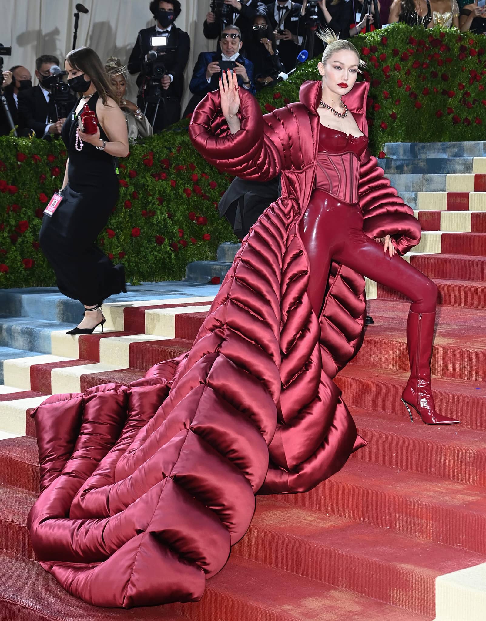 Gigi Hadid wears a massive quilted puffer coat and a latex jumpsuit with boned corset bustier from Versace