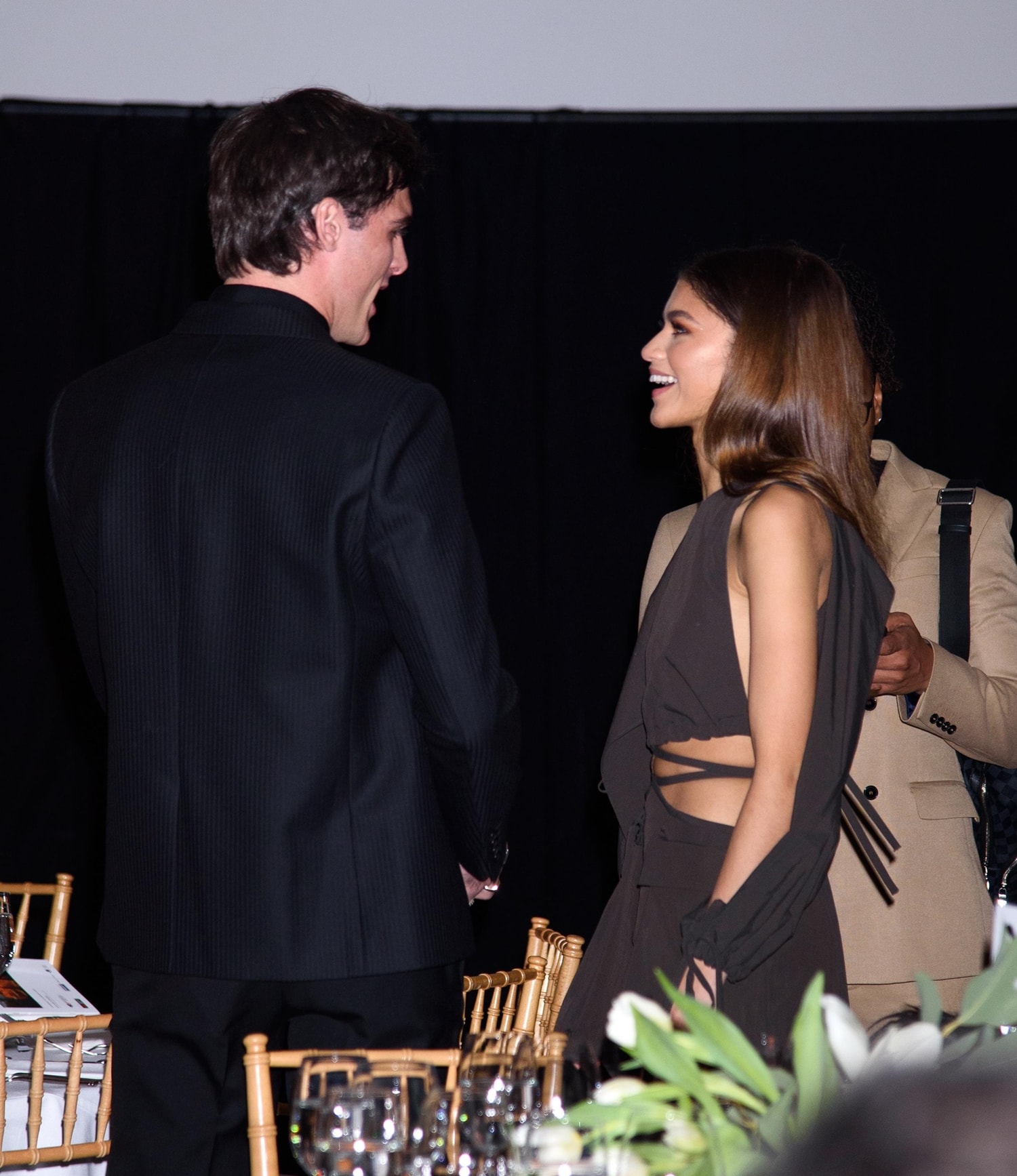 Zendaya, effortlessly chic in a cutout brown ensemble, shares a laugh with her much taller Euphoria co-star Jacob Elordi, whose 6ft 5 (195.6 cm) frame towers over her petite stature