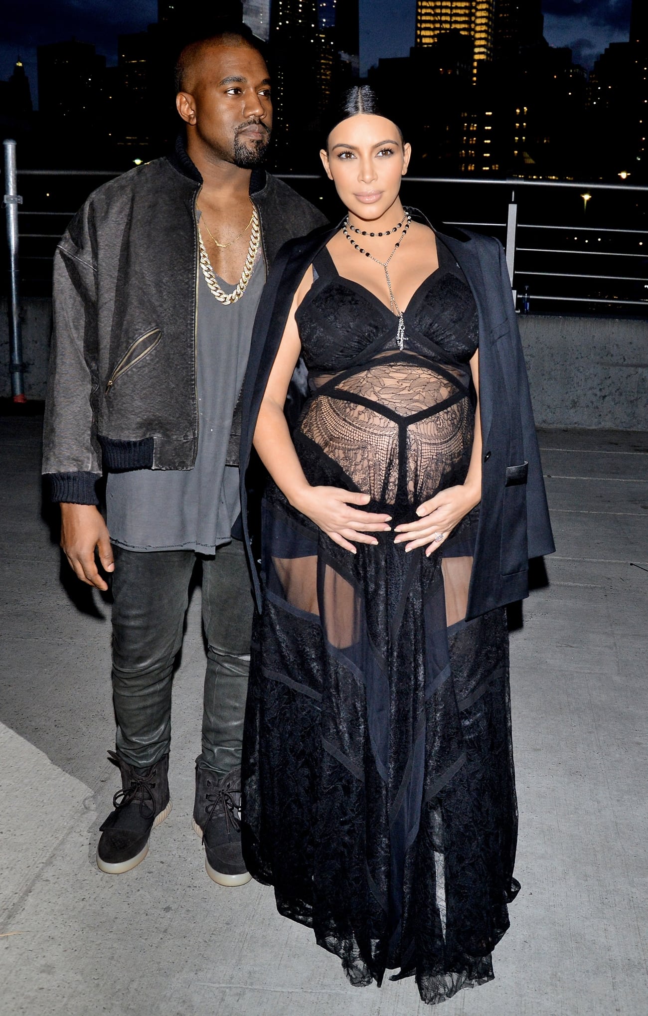 Kanye West and a pregnant Kim Kardashian arrive at the Givenchy Spring 2016 show during New York Fashion Week on September 11, 2015, with Kim pairing her sheer black lace maternity gown with minimalist heels while Kanye grounds his look in signature Yeezy suede boots