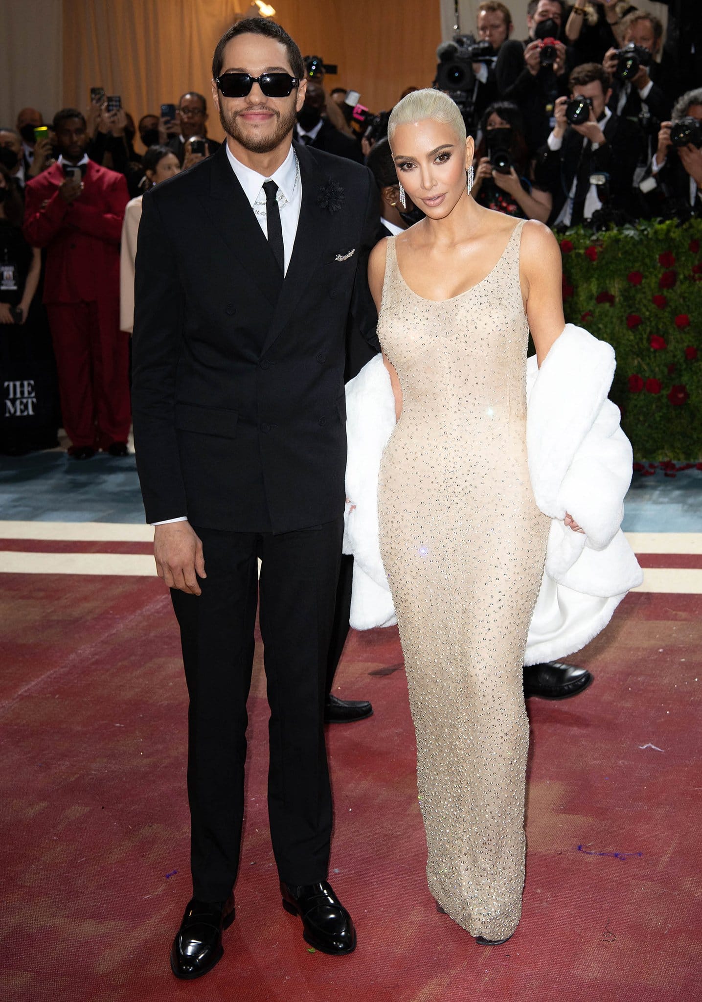 Kim Kardashian stuns in Marilyn Monroe’s iconic crystal-covered gown while Pete Davidson complements her look in a sharp black suit and sunglasses at the 2022 Met Gala