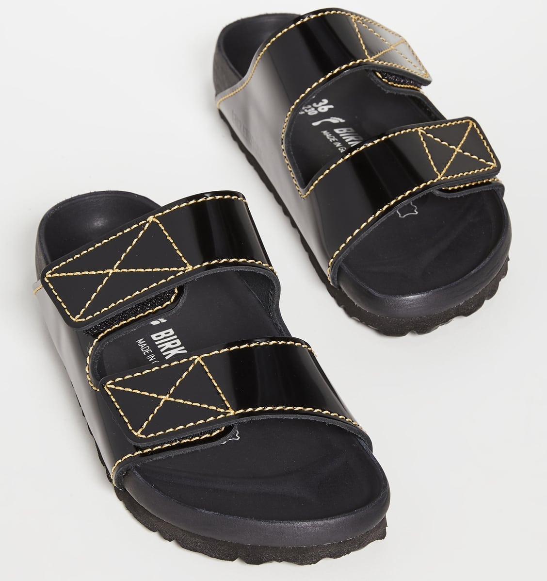 This striking pair of two-band Birkenstock x Proenza Schouler slides combines glossy patent leather with contrast topstitching and a legendarily comfortable footbed