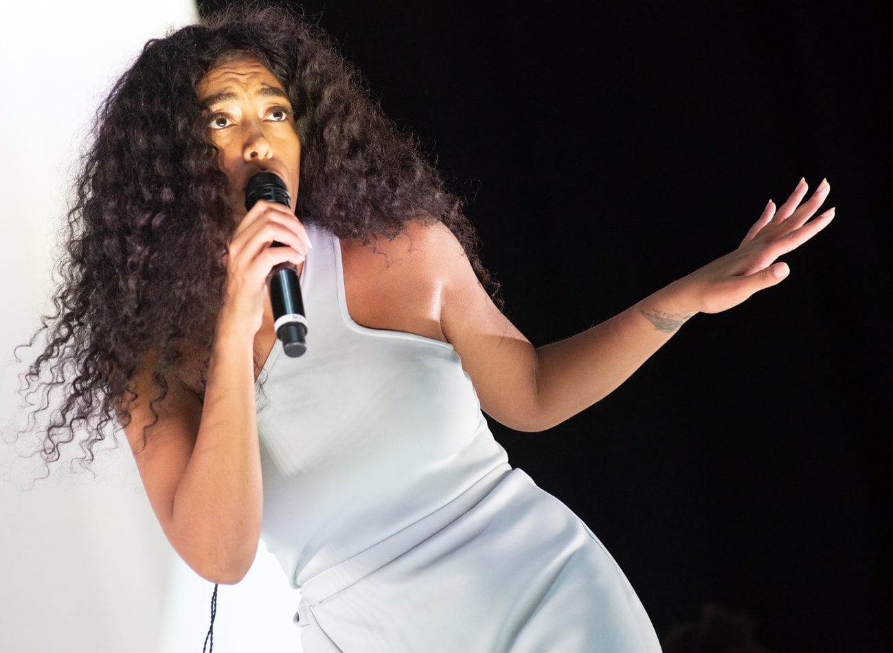 Solange Knowles performed on the Obelisk stage during Latitude Festival at Henham Park Estate in Southwold, England, on July 13, 2018, wearing a sleek asymmetrical white look while delivering an emotionally charged performance framed by her signature voluminous curls