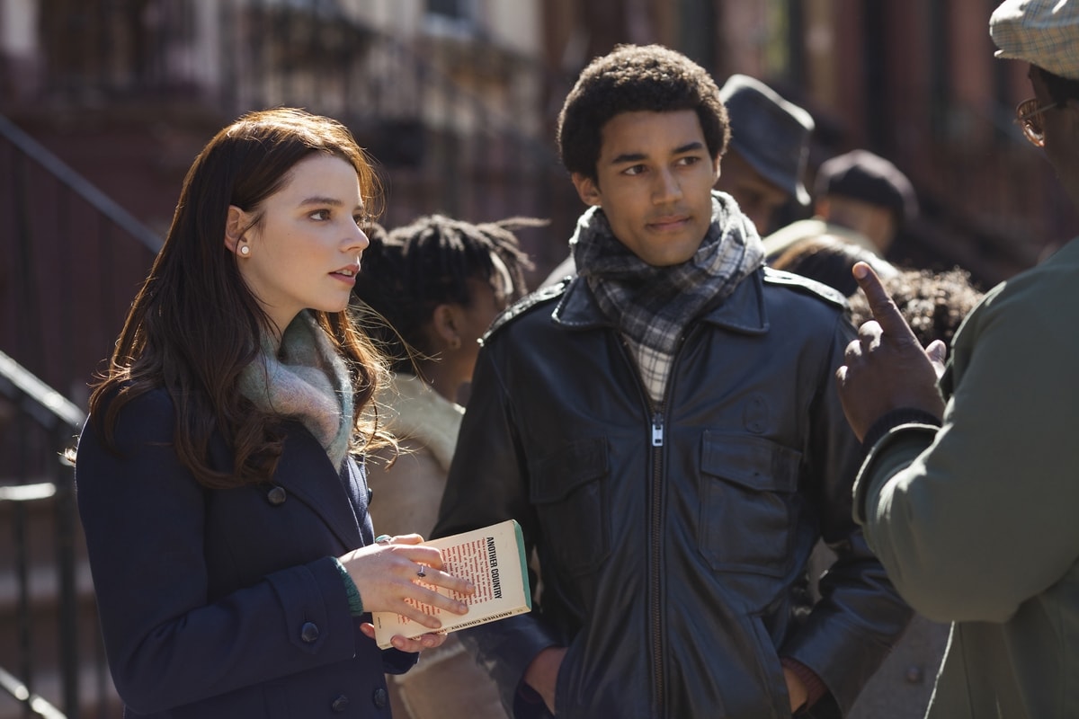 Anya Taylor-Joy brings collegiate charm to her role in Barry, styled in a classic navy coat, soft pastel scarf, and pearl earrings—perfectly embodying the intellectual poise of a 1980s university student