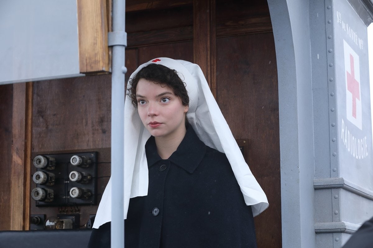 Anya Taylor-Joy portrays a young Irene Curie in Radioactive, wearing a traditional wartime nurse’s cloak and head covering—capturing the understated strength and historical realism of her supporting role
