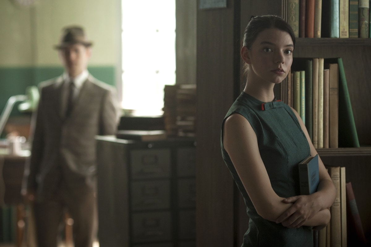 Anya Taylor-Joy channels vintage elegance as librarian Allie in Marrowbone, wearing a fitted, sleeveless green dress with a structured collar and subtle red accents that nod to the film’s mid-century aesthetic