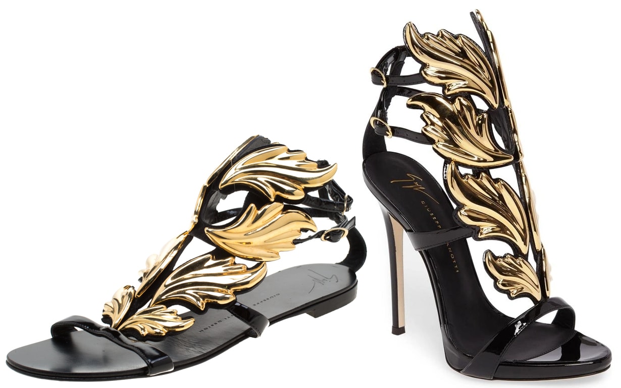 The Giuseppe Zanotti Cruel sandals feature striking gold wing detailing set against a sleek black design, offering a bold and luxurious statement in both stiletto and flat versions