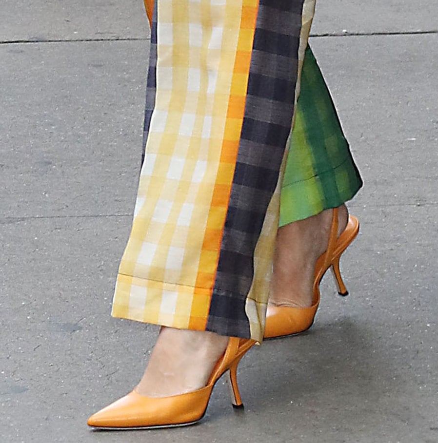 The By Far x Mimi Cuttrell slingback pumps feature a sharp pointed toe, smooth orange leather, and a slender curved stiletto heel that mirrors the bold color-blocking of Kristen Bell’s outfit