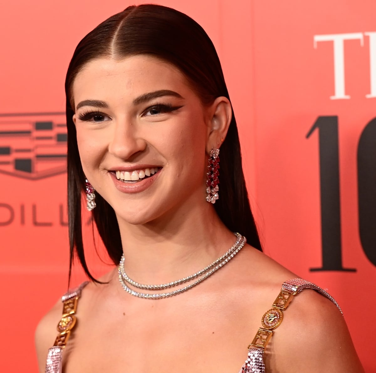 Her polished beauty look—sleek center-parted hair, winged eyeliner, and diamond-accented jewelry—complements the sculptural lines of the Fendace design