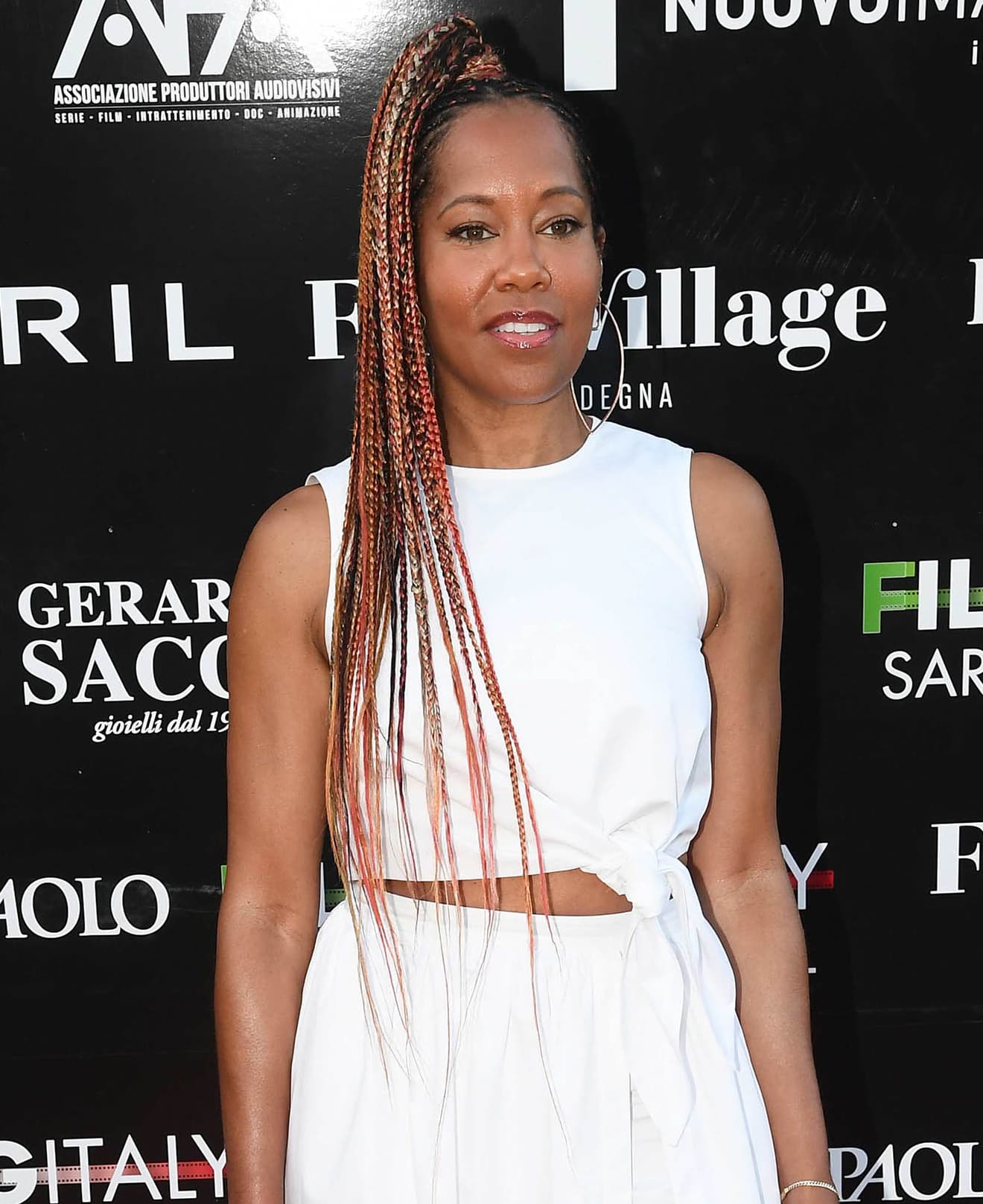 Regina King exudes effortless elegance with her long, orange-tinted braids styled in a sleek high ponytail, perfectly complementing her crisp white ensemble