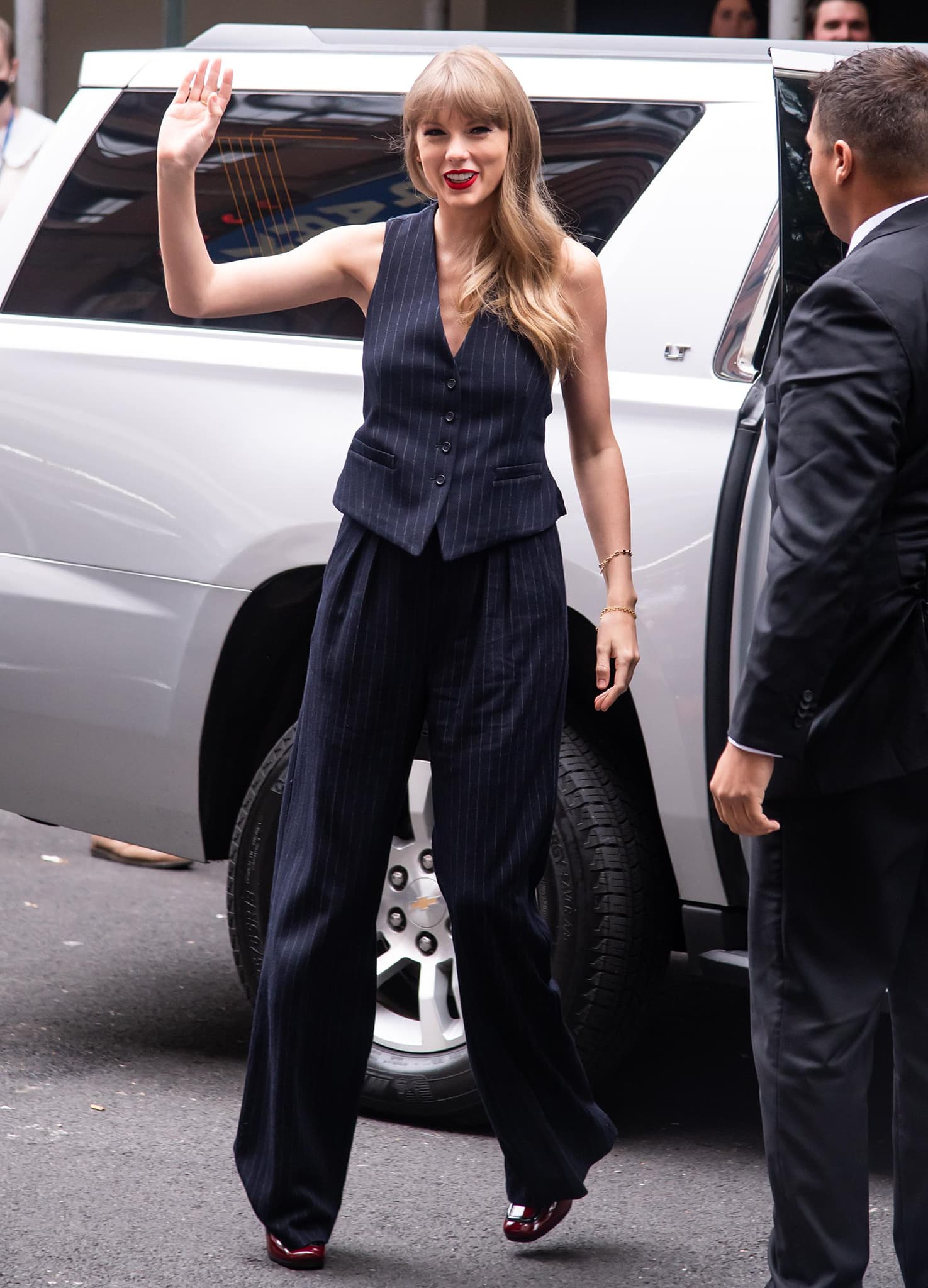 Greeting fans outside the venue, Taylor showcases the clean lines of her blazer-less pinstripe suit, grounded by sculptural red patent Prada heels