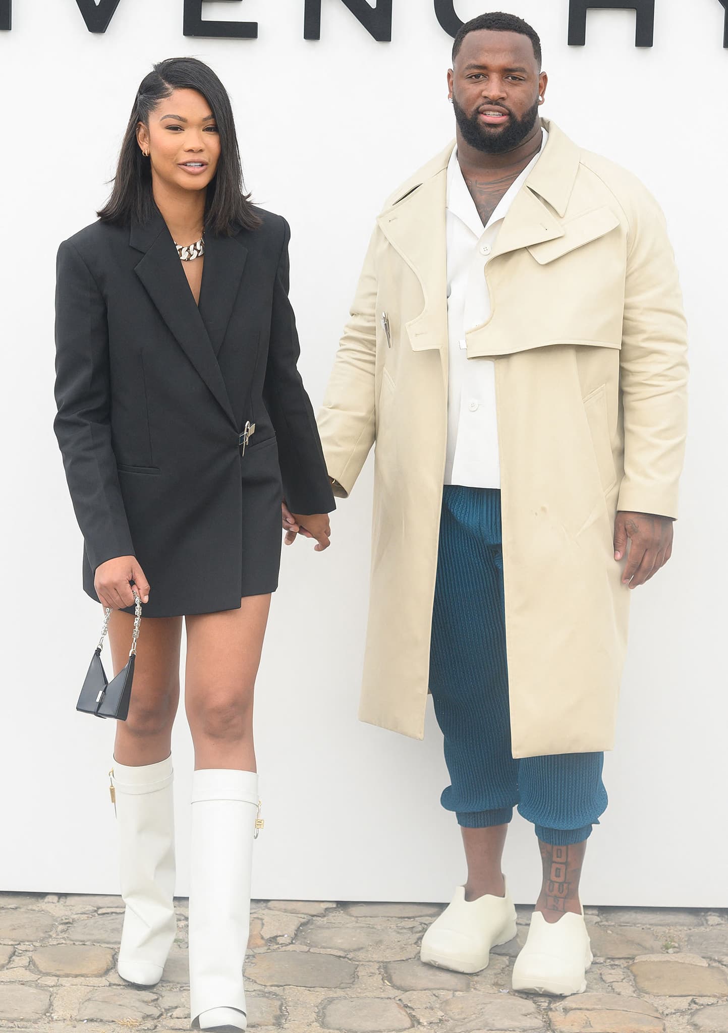 Chanel Iman wears white Givenchy Shark Lock wedge boots with a black blazer mini dress, while Davon Godchaux pairs his Givenchy look with Monumental Mallow low-top rubber shoes