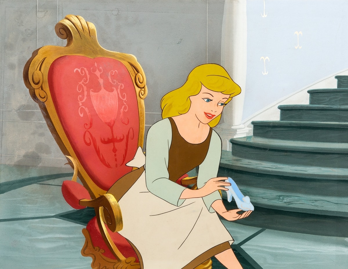 Cinderella delicately holds her magical glass slipper—the most iconic shoe in film history—in Disney’s beloved 1950 animated classic