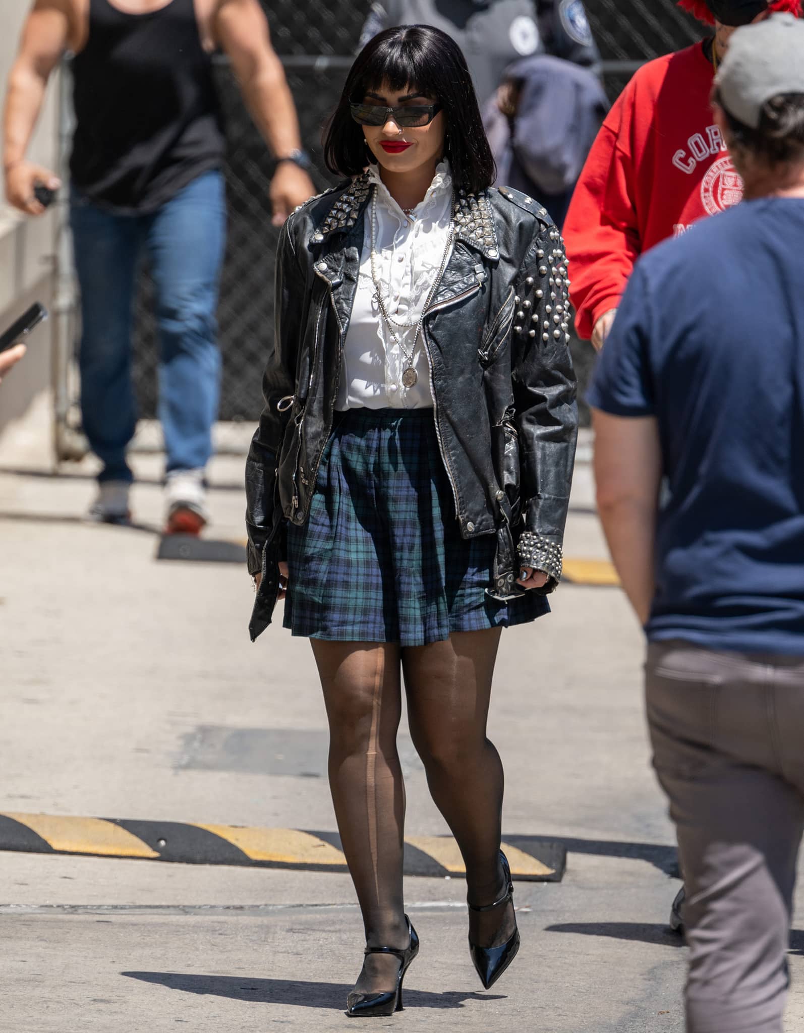 Demi Lovato arriving at the studio in a grungy ensemble with a plaid mini skirt, sheer tights, and a studded biker jacket