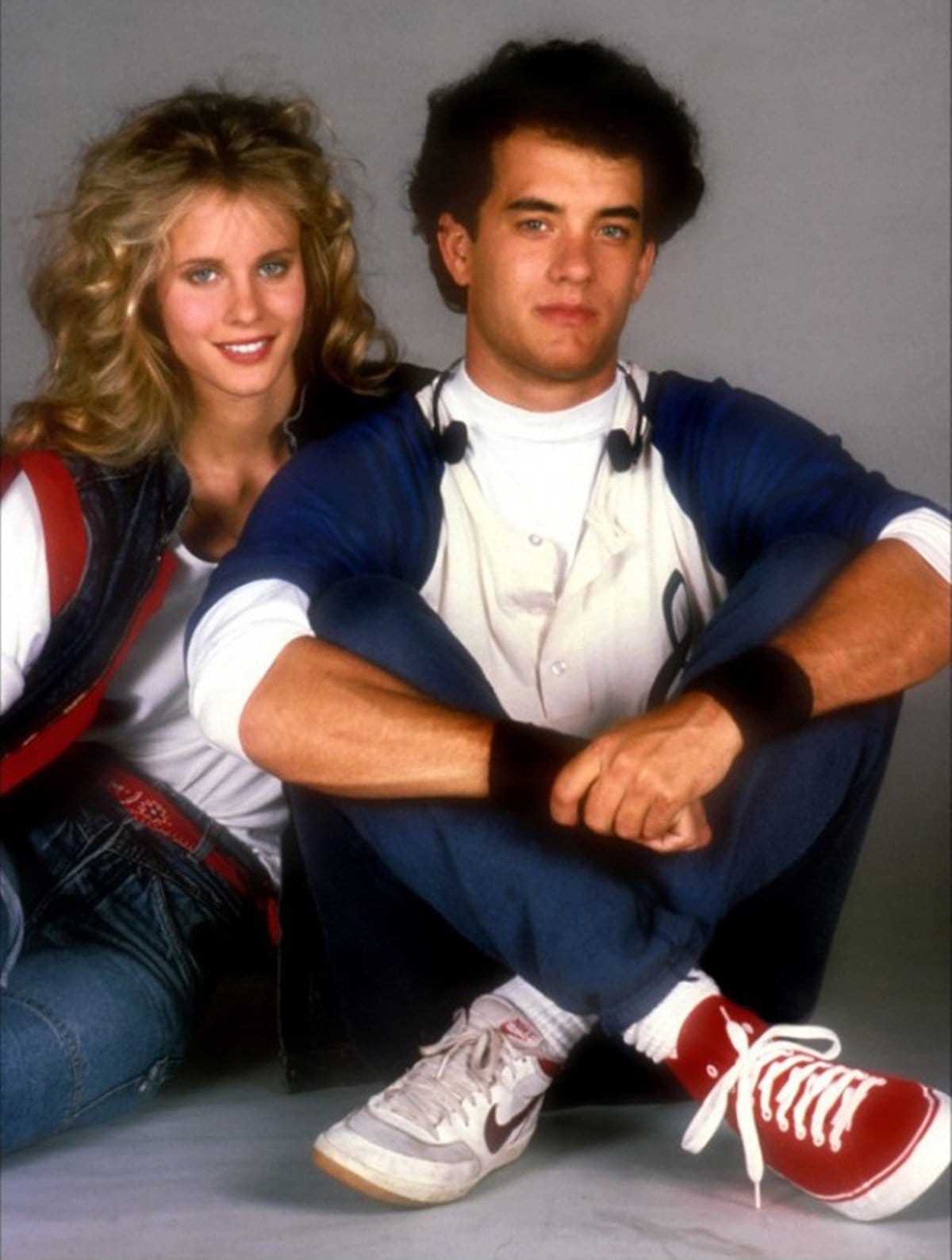 Tom Hanks wears mismatched sneakers—one classic white Nike and one bold red Converse All-Star high-top—while posing with Lori Singer in the 1985 comedy The Man with One Red Shoe
