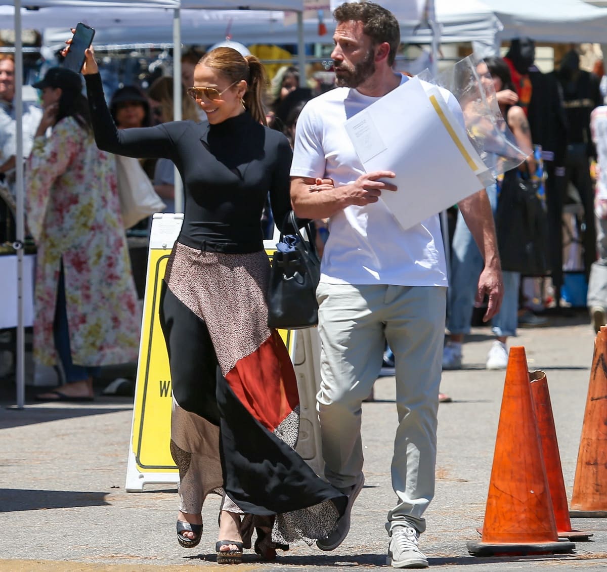 Jennifer Lopez brings polished summer glamour to the Melrose Trading Post in a fitted black turtleneck bodysuit, flowing color-block maxi skirt, and woven wedge sandals while strolling arm-in-arm with Ben Affleck in Los Angeles on July 3, 2022