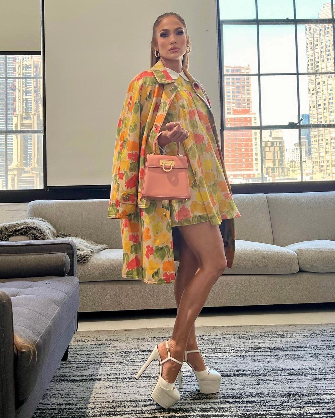 Jennifer Lopez styled her pastel Ferragamo top-handle bag with a floral Coach ensemble and sky-high white platform heels, leaning into the dramatic proportions she favored throughout the Halftime era