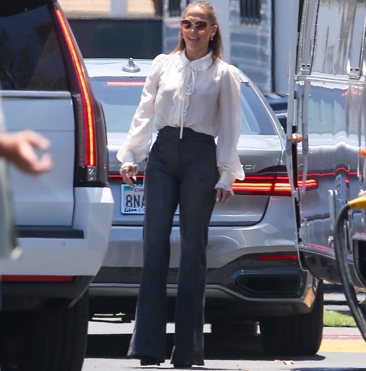 Jennifer Lopez balanced dramatic proportions with relaxed daytime styling, pairing a ruffled white blouse and Grey Ant flared jeans with towering platform heels during an outing in Los Angeles