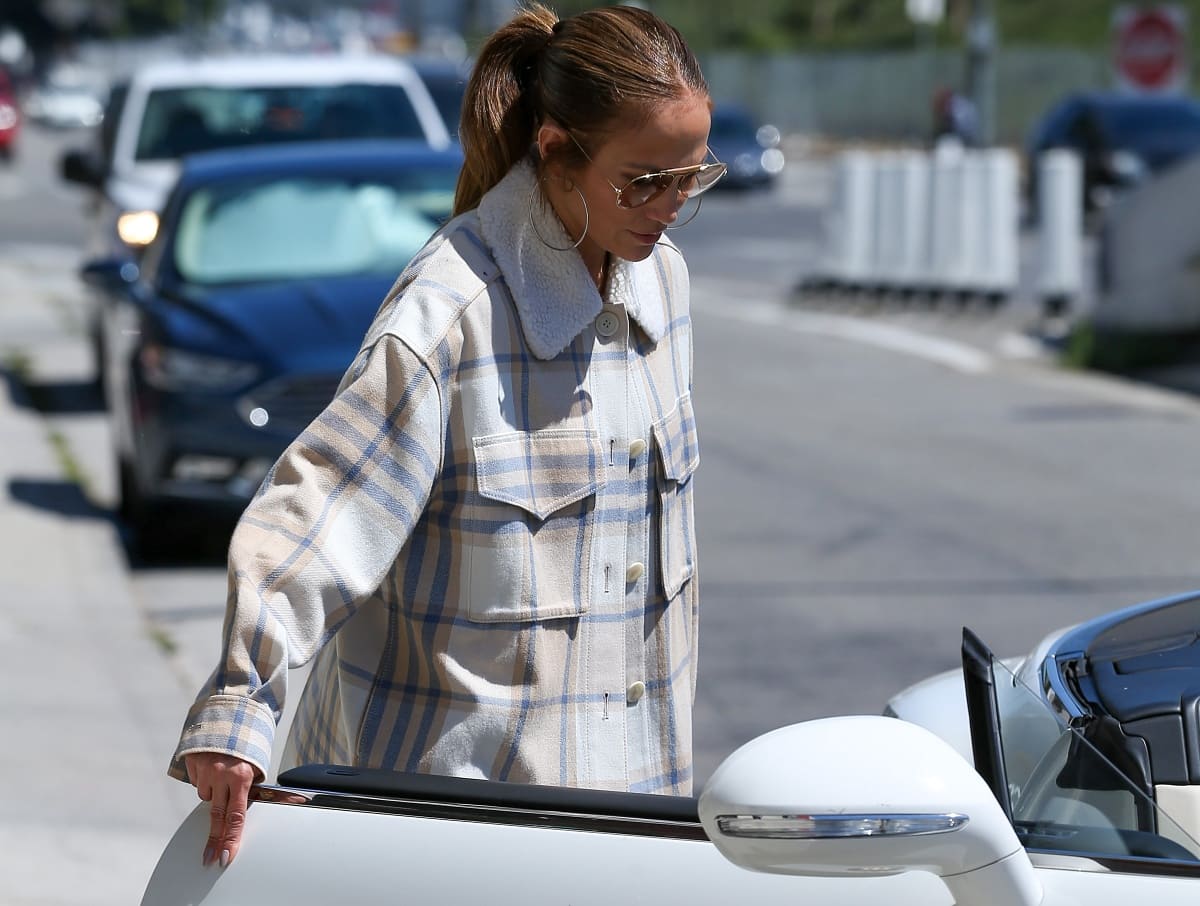Jennifer Lopez adding her signature glam touch with aviator shades, hoop earrings, and a white Hermès Birkin handbag